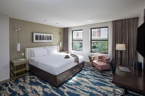 Een hotelkamer met een groot bed, een bureau, een stoel en uitzicht.