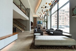 Eine moderne Lobby mit Treppe, Sitzgelegenheiten und großen Fenstern mit Blick auf die Stadt.
