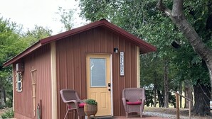 A small wooden cabin with a porch, two wicker chairs, a door, and a welcome sign. - Byrd Homestead - Hill Top (Carmen)