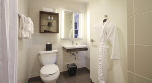 Een badkamer met toilet, wastafel, spiegel en een badjas hangend aan de muur.