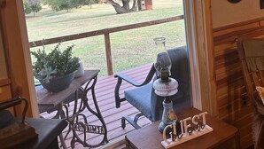 Una terraza de madera con una mesa y sillas, una planta en maceta y un cartel que dice 'GUEST'.