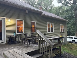 Une maison dotée d’une terrasse en bois, d’un espace salon extérieur et d’un escalier menant à l’entrée.
