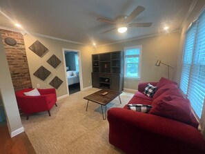 Un salon avec un canapé rouge, une table basse, une cheminée et un ventilateur de plafond.