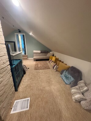 Une pièce avec un plafond en pente, un ensemble de canapés, une petite table et un miroir.