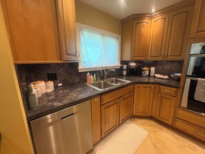 A kitchen with wooden cabinets, a stainless steel dishwasher, a coffee maker, and a sink. - 3k square foot house-sleeps 12 people comfortably. (Coloma)