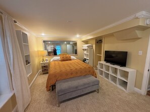 Ein Hotelzimmer mit Bett, Fernseher, Sitzbank, Spiegel und Ablageflächen.
