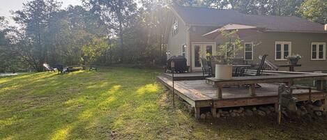 Une maison avec une terrasse, du mobilier d’extérieur et un barbecue.