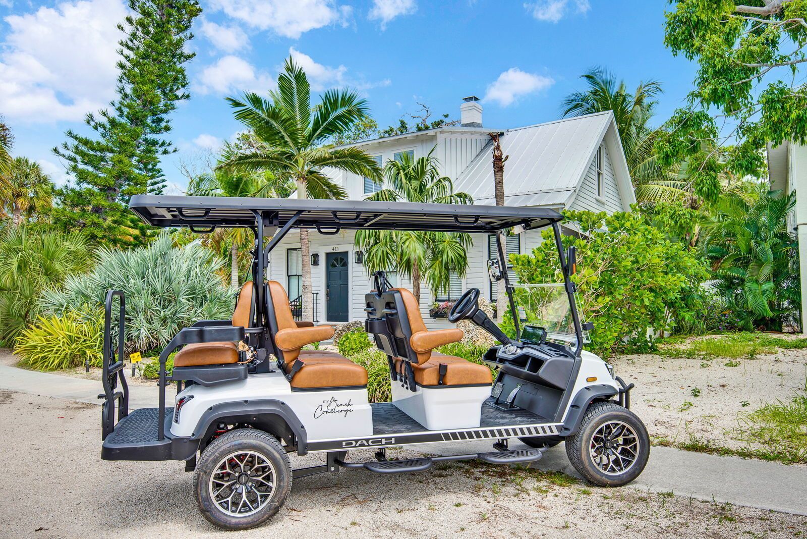 Ein Golfmobil steht vor einem Haus mit weißer Fassade und schwarzem Dach.