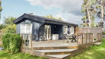 A cabin with a deck, outdoor seating, and a small porch area.