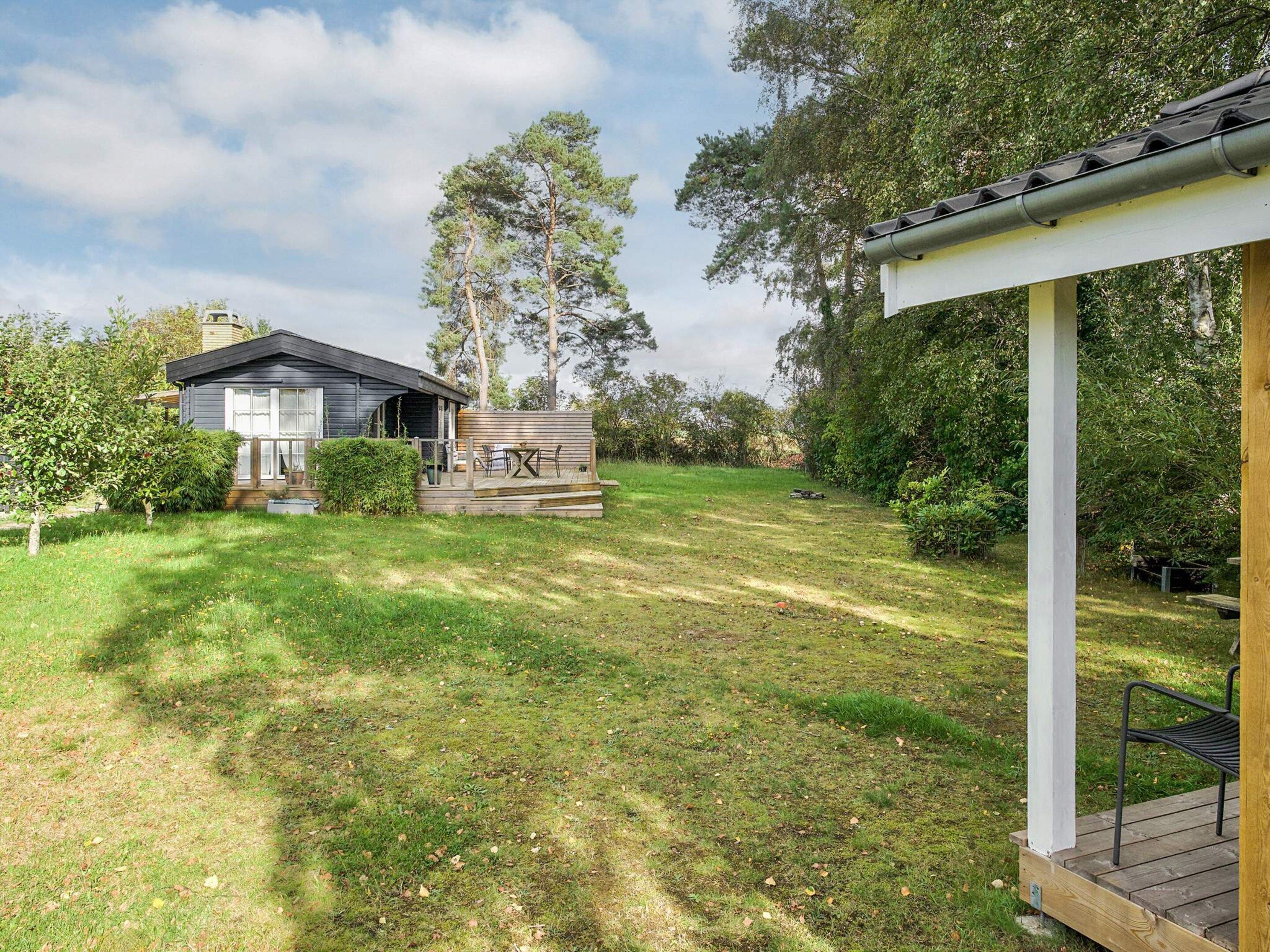 A modern house with a deck, surrounded by a well-maintained lawn and trees.