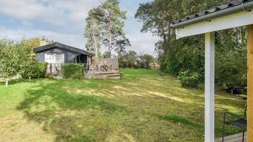 A modern house with a deck, surrounded by a well-maintained lawn and trees.