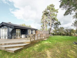 A cabin with a deck, a patio, and a view of trees. - 4 Star Holiday Home in Olsted (Olsted)