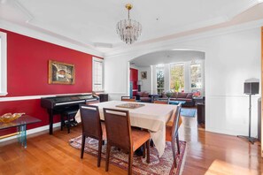 A dining area with a piano, a table set for four, and a chandelier. - Spacious 4BR/4BA Vancouver Retreat | Near Downtown & UBC (Vancouver)