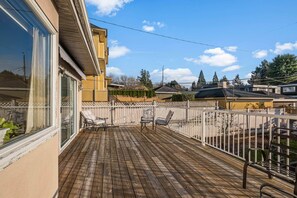 A wooden deck with two chairs and a table, surrounded by a white fence. - Spacious 4BR/4BA Vancouver Retreat | Near Downtown & UBC (Vancouver)
