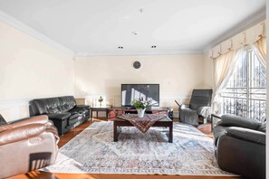A living room with a sofa, armchairs, a coffee table, and a TV. - Spacious 4BR/4BA Vancouver Retreat | Near Downtown & UBC (Vancouver)