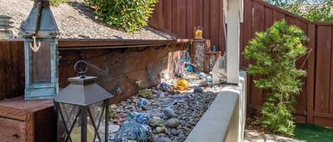 A garden with a wooden fence, decorative lanterns, and a variety of stones and shells.