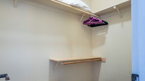 A corner of a room with a wooden shelf and a hanging rack with clothes. - Ritz del Rio by Avantstay Single-level + BBQ Patio + Outdoor TV Quiet Cul-de-sac (Paso Robles)
