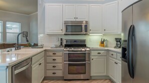 A modern kitchen with white cabinetry, stainless steel appliances, and a dishwasher. - Ritz del Rio by Avantstay Single-level + BBQ Patio + Outdoor TV Quiet Cul-de-sac (Paso Robles)