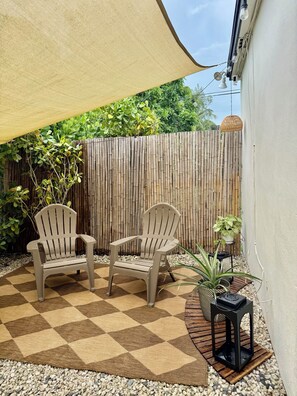 An outdoor seating area with two chairs, a checkered rug, and a potted plant. - Modern & Stylish 1 Bedroom Retreat  Full Kitchen  Private Patio & Free Parking (North Miami)