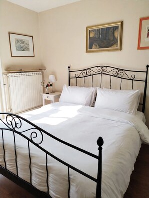 A bedroom with a bed, a nightstand, a lamp, a radiator, and a painting on the wall. - A 19th-century farmhouse with spacious grounds surrounded by greenery and a swimming pool (Molise)