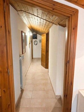 A hallway with wooden doors, a radiator, and wall-mounted lights.