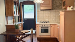 A kitchen with wooden cabinets, a dining table, and a hanging light fixture. - A 19th-century farmhouse with spacious grounds surrounded by greenery and a swimming pool (Molise)