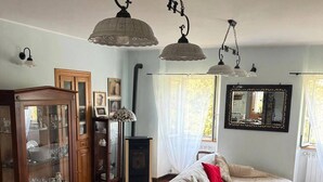 A dining area with a table set for two, a cabinet with glass doors, and a bed with a patterned rug. - A 19th-century farmhouse with spacious grounds surrounded by greenery and a swimming pool (Molise)