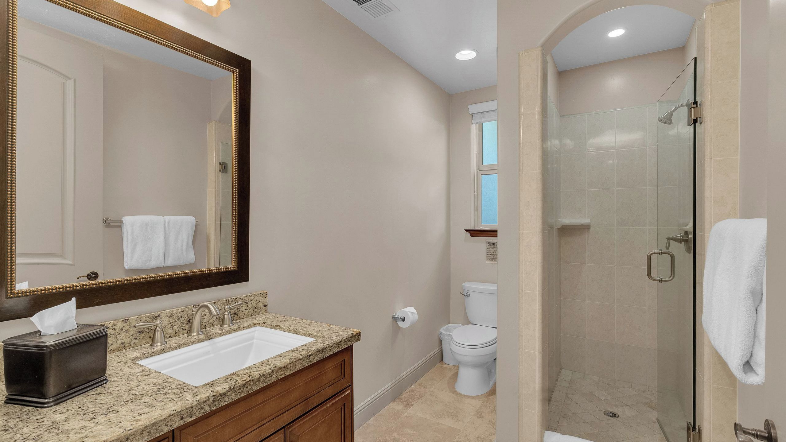 A bathroom with a sink, mirror, toilet, and shower.
