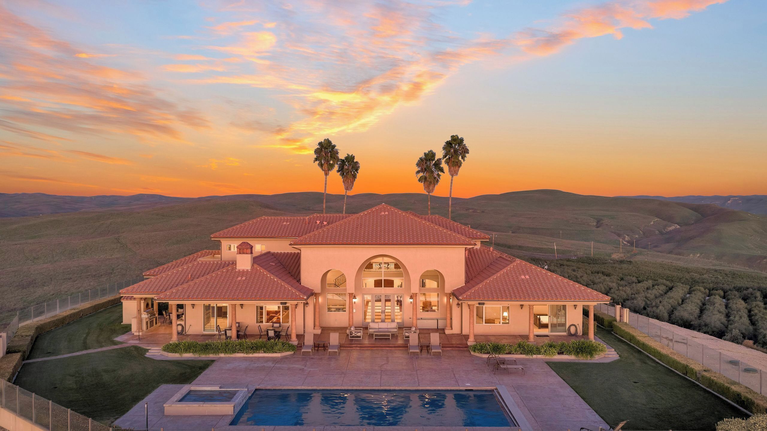Una casa grande con piscina, varias habitaciones y vistas a las colinas circundantes.