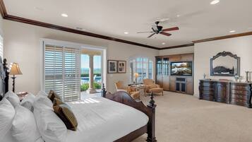 A bedroom with a large bed, a ceiling fan, and a view of the outdoors.