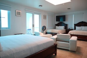 Une chambre d’hôtel avec un grand lit, deux petits lits, un bureau et une chaise.