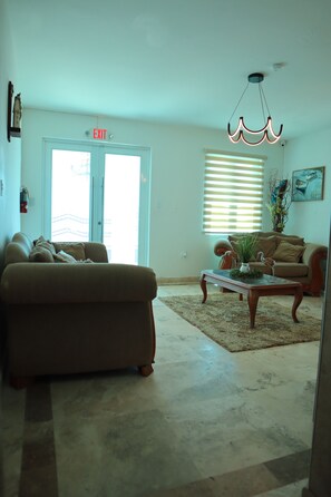 A living room with a sofa, a coffee table, and a painting on the wall. - La Bahia Guest House/ Front beach 2 private (Aguadilla)