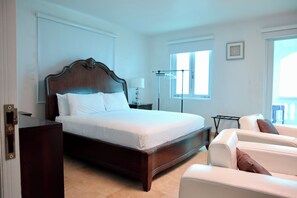 A hotel room with a large bed, a bedside table, a lamp, a chair, and a window. - La Bahia Guest House/ Front beach 2 private (Aguadilla)