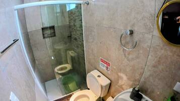 Casa de banho com chuveiro envidraçado, sanita e lavatório.