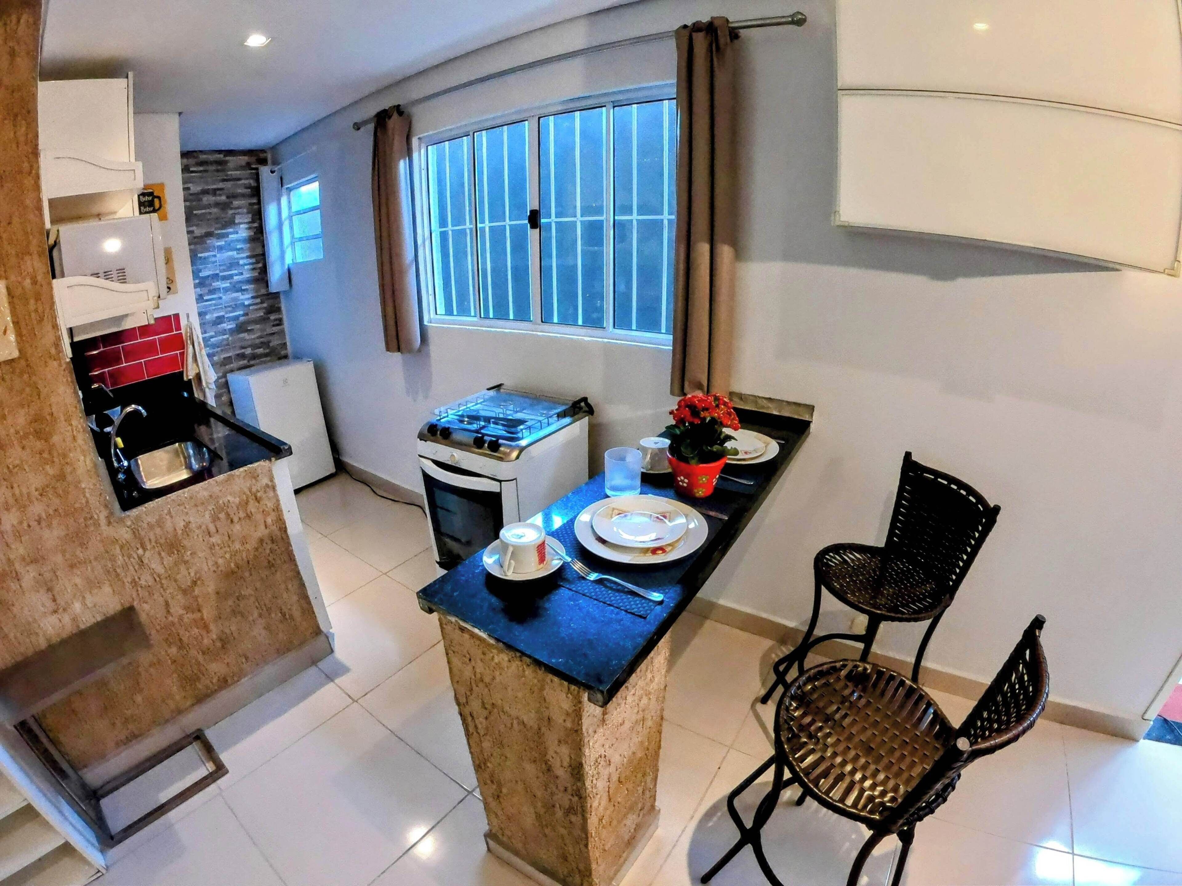 A compact kitchen with a gas stove, a small oven, and a dining area with a table and two chairs.