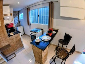 A compact kitchen with a gas stove, a small oven, and a dining area with a table and two chairs.