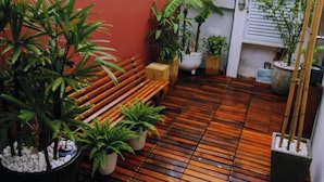 A wooden deck with potted plants and a bench.
