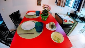 A dining area with a red table, plates, cutlery, and a potted plant.