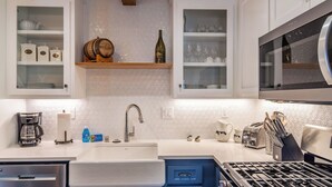 A modern kitchen with white cabinetry, a built-in oven, a stainless steel range hood, and a double sink. - The Top Shelf by Avantstay Two Master Suites + Balconies Downtown Paso Robles Wine Country (Paso Robles)