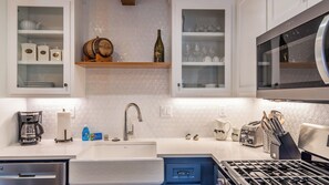 A modern kitchen with white cabinetry, a built-in oven, a stainless steel range hood, and a double sink. - The Top Shelf by Avantstay Two Master Suites + Balconies Downtown Paso Robles Wine Country (Paso Robles)