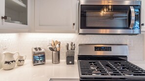 A modern kitchen with a stainless steel microwave, a toaster, and a gas stove. - The Top Shelf by Avantstay Two Master Suites + Balconies Downtown Paso Robles Wine Country (Paso Robles)