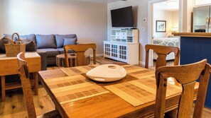 A living room with a sofa, wooden dining table, chairs, a television, and a cabinet. - The Top Shelf by Avantstay Two Master Suites + Balconies Downtown Paso Robles Wine Country (Paso Robles)