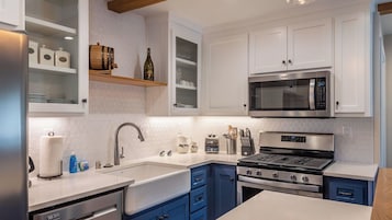 Una cocina moderna con armarios blancos, estufa de acero inoxidable, microondas y horno empotrado.