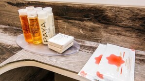 A counter with bottles of PAYA skincare products, a white soap bar, and a package of makeup remover wipes. - Accessible King Room (Anaheim)