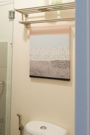 A bathroom with a shower, toilet, and a towel rack.