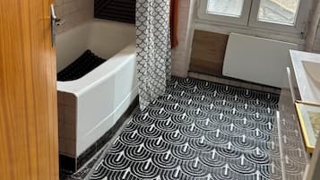 Un bagno con una vasca, una tenda da doccia, un tappeto decorato e una finestra.