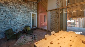 A room with a stone wall, wooden furniture, and a large window. - Ronchetto - Appartamento Cascina (Cunardo)