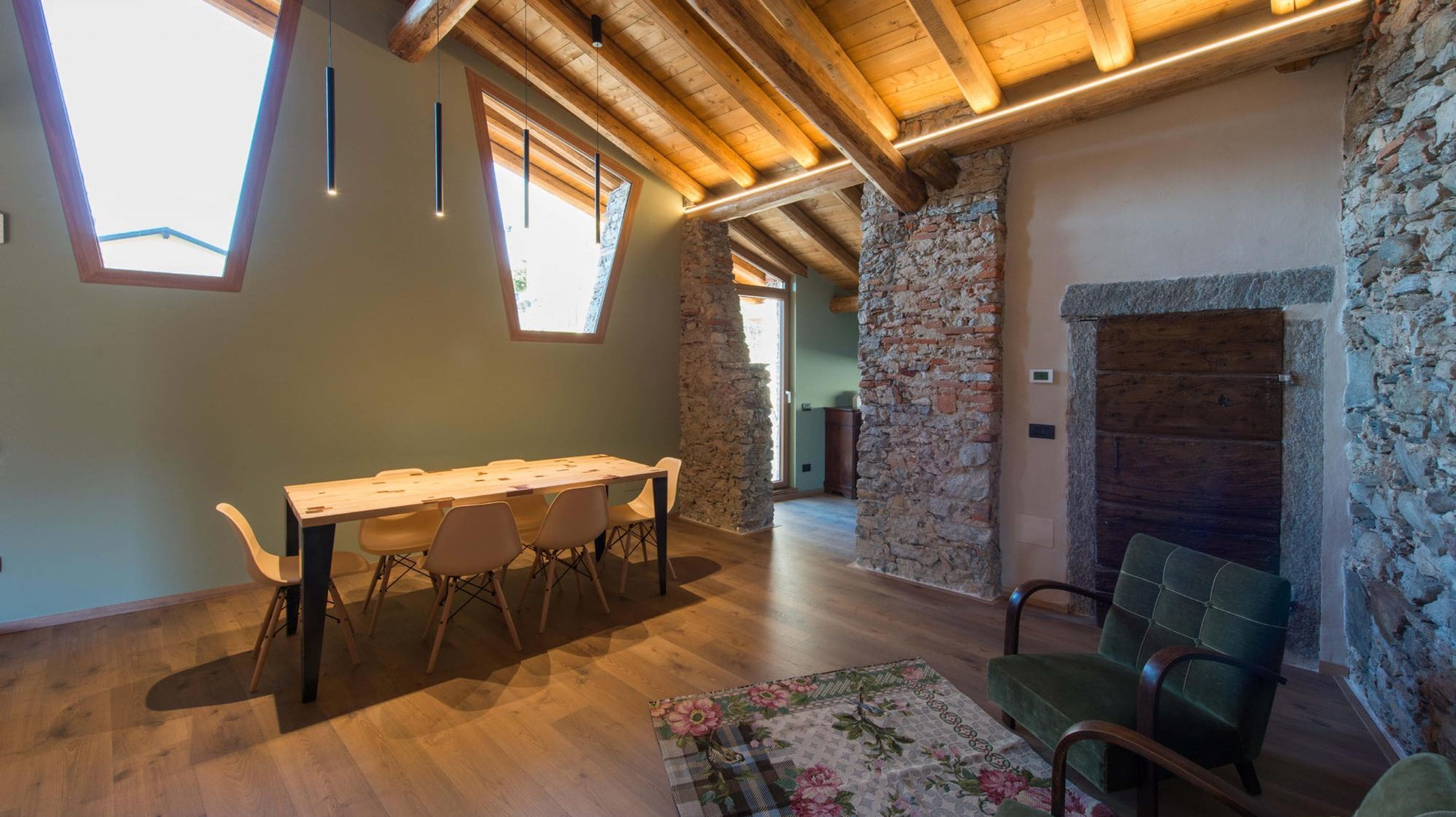 A spacious room with a wooden table and chairs, stone walls, and a fireplace.