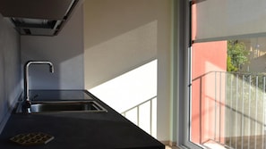 Cozinha com pia de aço inoxidável e janela com vista para uma varanda.