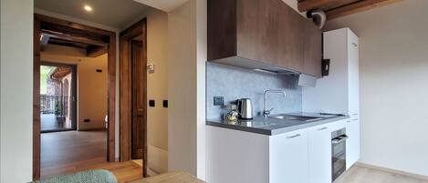Una cocina moderna con techo de madera, armarios blancos y un lavamanos de acero inoxidable.